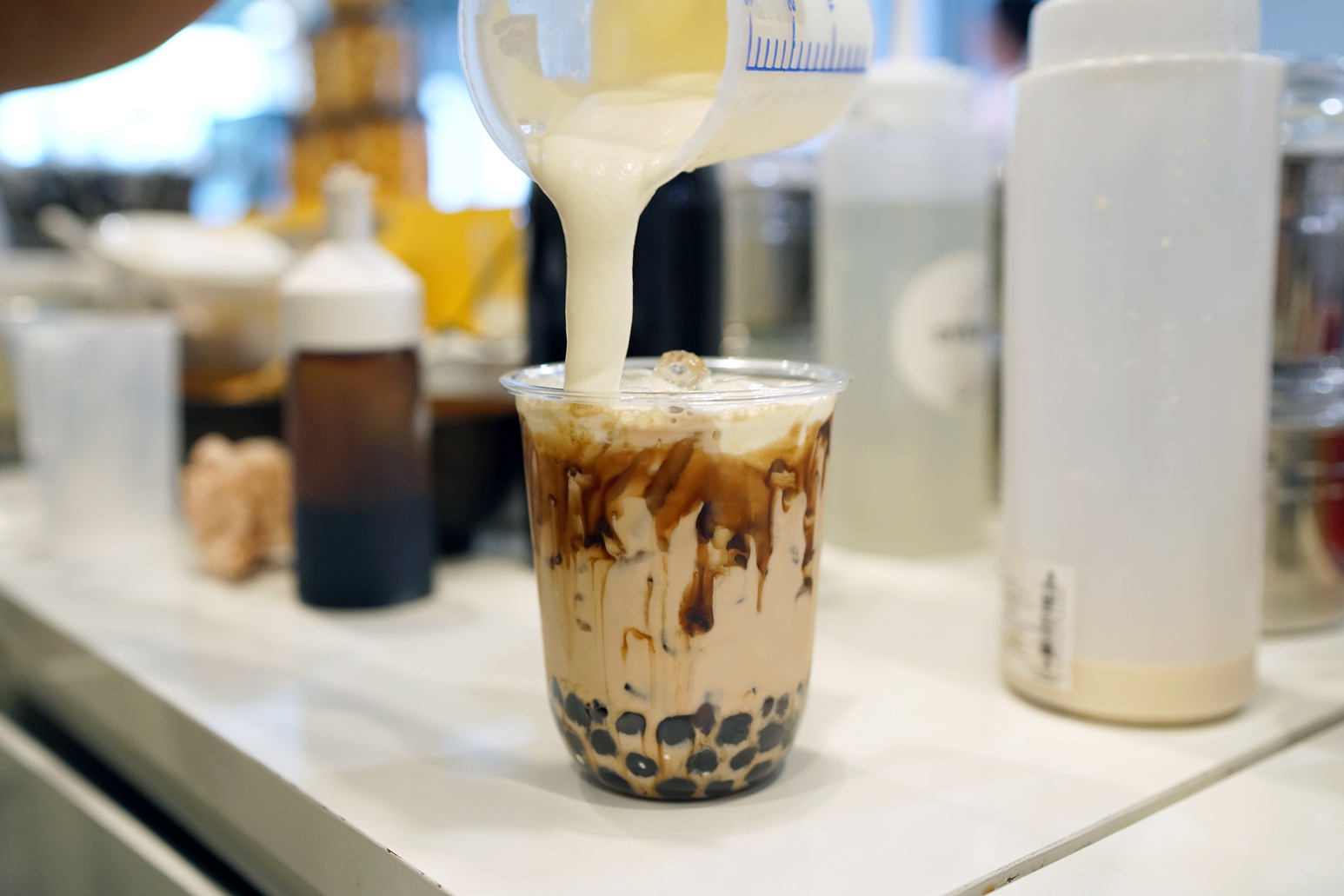 Bubble Milk Tea - Pouring cream cheese into glass of milk tea with black sugar syrup (Kuromitsu) and hot black pearl (Boba).